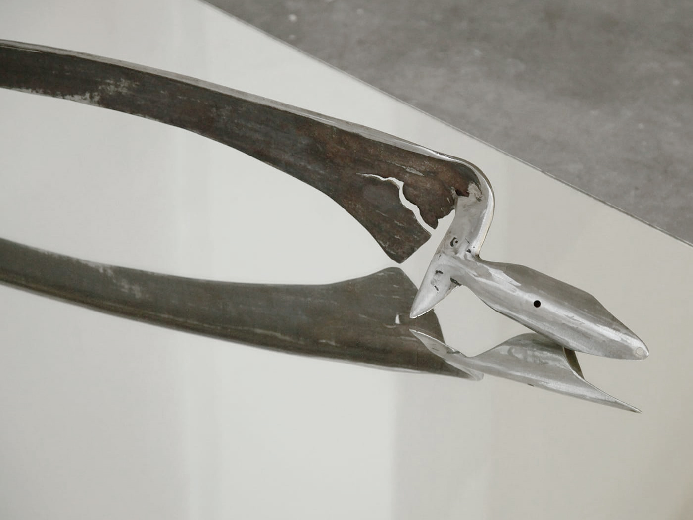 Close-up of a steel war scythe on a reflective surface.