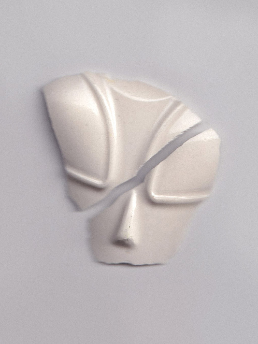 A cast of a non-human face made of glazed plaster.