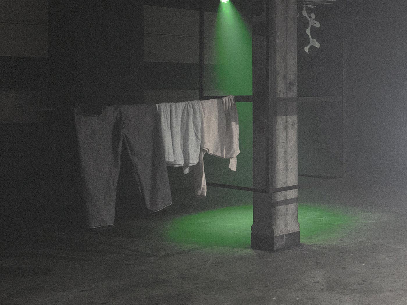 Three items of clothing hang on a steel cable to dry, with a green spotlight and a cut molecular structure in the background.