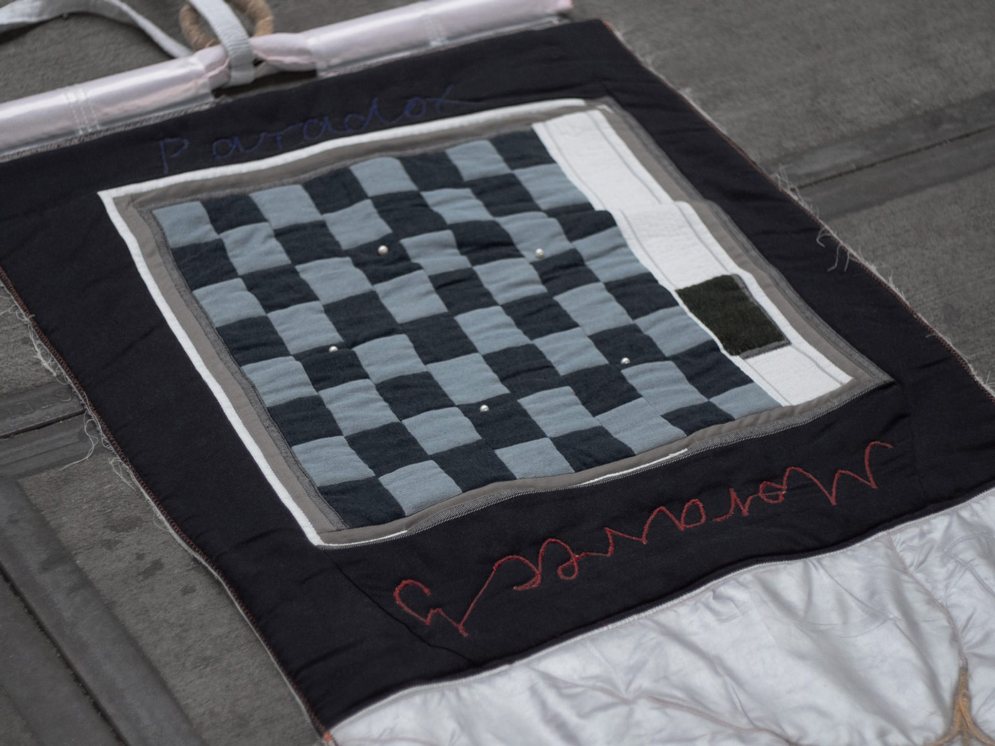 A chessboard with tiles in two different shades of blue. Five freshwater pearls can be seen in a circular arrangement on the chessboard. There is a scroll bar on the right-hand side of the chessboard. The window is framed in black fabric, with Moravec's Paradox written on the frame.