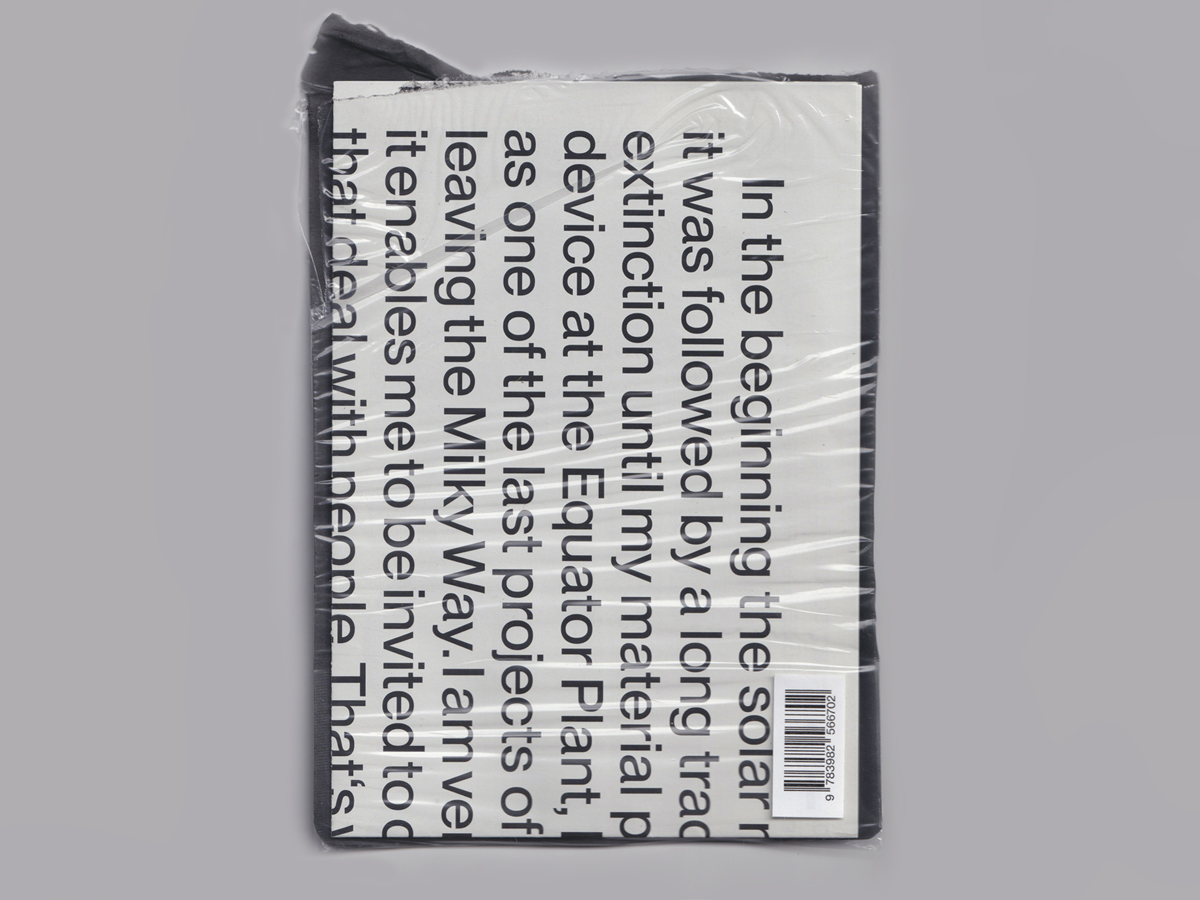 A cellophane-folded poster on which fragments of text can be read in a sans serif font. In the bottom corner a barcode of the ISBN number 9783982566702.